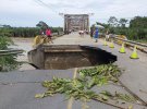 Люди стоять на мосту через річку Ла Естрелла, пошкоджену повенями через сильні дощі.
