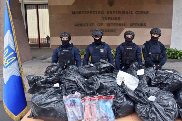Полицейские охраняют 368 кг героина изъятого у членов транснациональной группы по торговле наркотиками.