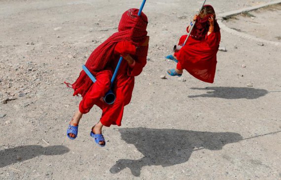 Афганские девушки закрывают лицо руками, катаясь на качелях в первый день мусульманского праздника Курбан-байрам в Кабуле, 11 августа 2019 года