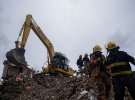 Гаїтянські пожежники шукають вцілілих під завалами зруйнованої будівлі після землетрусу.