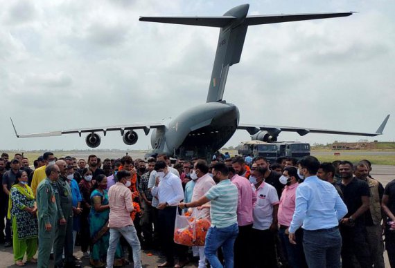 Официальные лица индийской миссии в Афганистане и эвакуированные гражданские Индии изображены после того, как их рейс приземлился в городе Джамнагар на западе Индии для заправки топливом по пути в Дели, Индия.
