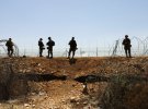 Израильские солдаты охраняют забор, ведущий на оккупированный Израилем Западный берег, в рамках поисковых работ по задержанию шести палестинцев, сбежавших из тюрьмы Гильбоа ранее на этой неделе, у деревни Мукибила на севере Израиля