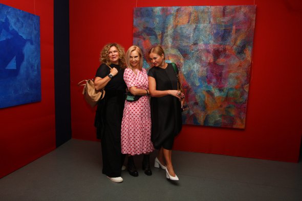 Художниця Оксана Мась (ліворуч) позує з подругами навпроти своєї роботи "Ментальний колір"