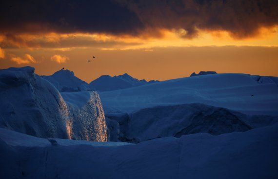 Солнечный свет отражается от ледяной стены айсберга во время заката в заливе Диско недалеко от Илулиссата, Гренландия