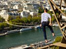 Французский акробат Натан Полин идет по канату от Эйфелевой башни через Сену в Париже