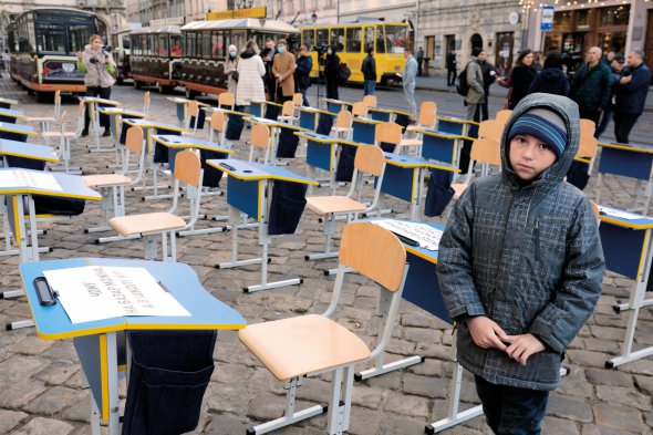 Школяр стоїть біля парт під міською радою Львова 3 листопада. Їх принесли батьки та вчителі. Вимагали поновити навчання у школах із повністю вакцинованими колективами. В міськраді пообіцяли проаналізувати захворюваність на коронавірус серед дітей. Якщо показники будуть незначні, то до очного навчання повернуться учні молодших класів