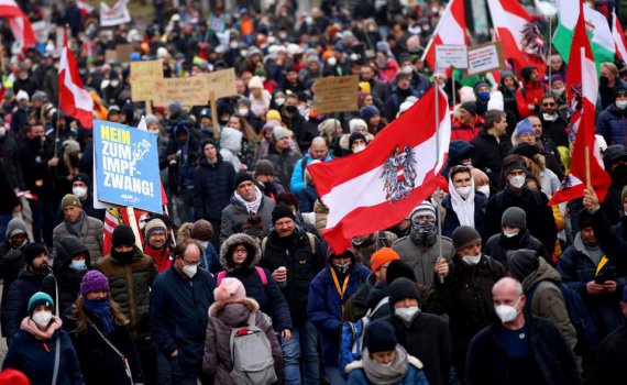 Демонстранти тримають прапори та плакати під час маршу протесту проти обмежень через коронавірус та обов'язкову вакцинацію у Відні, 4 грудня