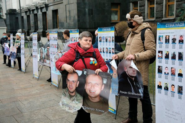 Люди тримають фото зниклих і полонених у зоні операції Об’єднаних сил родичів під час акції ”Живі, кинуті, забуті” під Офісом президента 3 грудня. Принесли 120 портретів. Вимагають профінансувати роботу Комісії з питань осіб, зниклих безвісти за особливих обставин