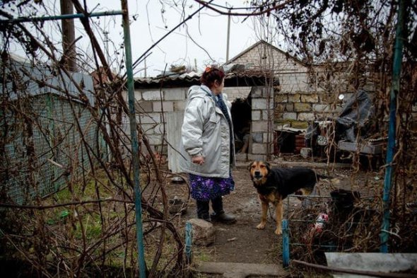 Світлана Хайтулова стоїть на своєму подвір'ї в селі Гранітне на Донеччині. Її будинок пошкодив снаряд бойовиків