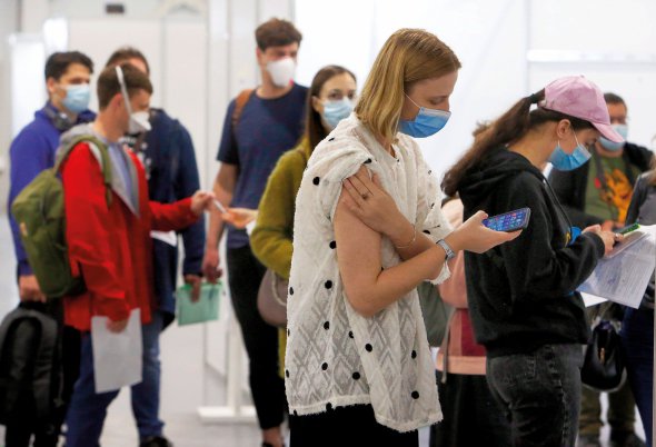 Люди стоять у черзі на вакцинацію від коронавірусу в столичному Міжнародному виставковому центрі, травень 2021 року. Навесні пункти щеплення почали відкривати в торговельних і офісних центрах, будинках культури, на вокзалах