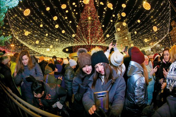 Дівчата фотографуються на відкритті головної ялинки країни на Софійській площі в Києві 18 грудня. Увечері засвітили гірлянду завдовжки 10 кілометрів. 31-метрове дерево вбрали понад 20 тисячами прикрас червоного та золотавого кольорів. Навколо встановили різдвяний вертеп. Працюватиме до 19 січня 2022 року