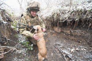 Жінка-військовослужбовець гладить собаку в зоні проведення операції Об’єднаних сил на Донеччині 10 грудня 2021 року. 57 тисяч жінок служать і працюють в українській армії. Це один із найвищих показників серед усіх армій світу