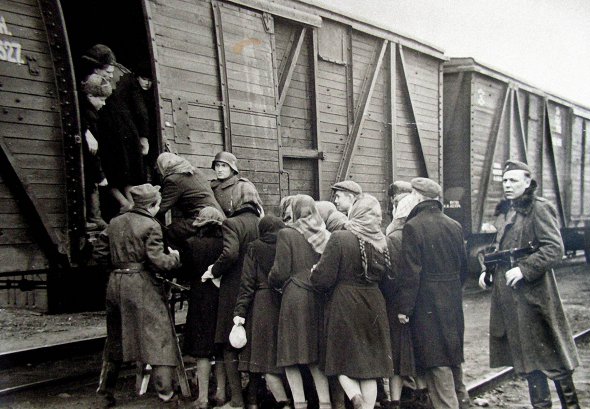 Жителів українського містечка садять у товарний вагон, щоб відправити на роботу в Німеччину, 1942 рік. Обіцяли гідну оплату й добрі умови, тому багато хто їхав добровільно