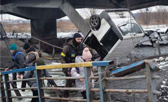 Український військовий допомагає дитині перейти зруйнований міст в Ірпені