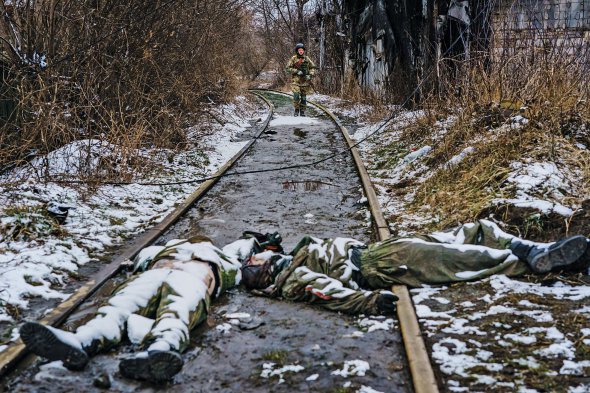 Український військовий підходить до трупів окупантів на рейках після бою на околицях Ірпеня 1 березня