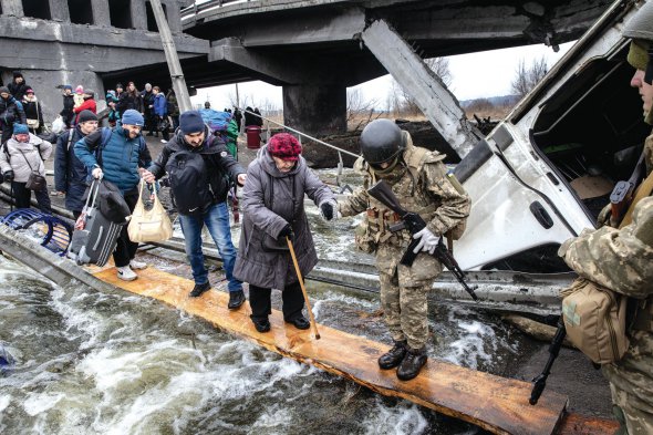 Люди йдуть підірваним російськими обстрілами містом в Ірпені поблизу Києва. 7 березня 2022 року