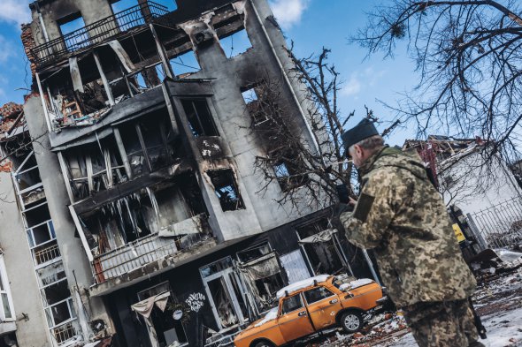 Солдат перед разрушенным зданием в Харькове 