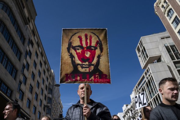 Протестующий держит плакат с лицом Путина и словом «Убийца» во время протеста против вторжения России в Украину в Мадриде 