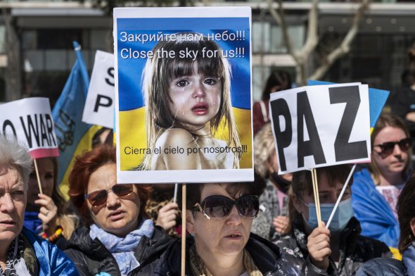 Протестующий держит плакат с надписью «Закройте для нас небо» во время акции против вторжения России в Украину в Мадриде 