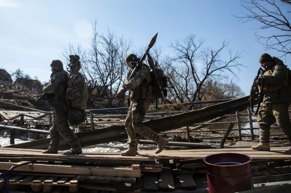 Украинские силы с реактивными гранатометами переходят под поврежденным мостом в Ирпене, 12 марта