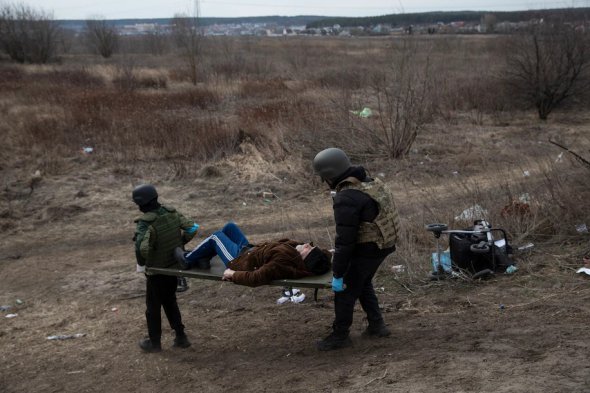 Солдати територіальних сил оборони допомагають чоловікові в Ірпені, 12 березня