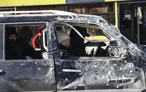 Люди їдуть у понівеченому від обстрілів автомобілі з Ірпеня. Місто — одна з гарячих точок російсько-української війни. Більшість житлових будинків та інфраструктури розбомблені. Військові та волонтери намагаються евакуювати якомога більше жителів у безпечні регіони. Періодично транспорт із цивільними обстрілюють росіяни.