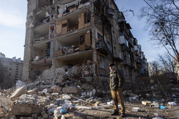 Мужчина среди обломков перед жилым комплексом, который сильно пострадал в результате удара России, 18 марта, Киев 