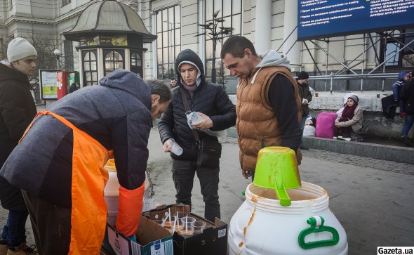 Горячие блюда возле вокзала волонтеры разливают в стаканчики и раздают беженцам