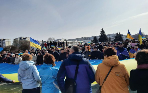 Жителі міста Славутич тримають великий жовто-синій прапор на центральній вулиці міста 26 березня. Уранці того дня у місто увійшли російські окупанти