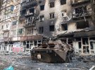 Мариуполь, 23.03.2022: Уничтоженный бронеавтомобиль БТР, предположительно принадлежащий защитникам батальона "Азов", стоит возле разрушенного жилого комплекса в осажденном украинском городе.