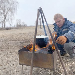 Рибну юшку готує на вогнищі чернігівець Микола Семенченко. Коли в обласному центрі стало небезпечно, виїхав із родичами жити в село