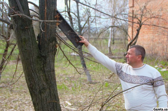 Мэр Ахтырки Павел Кузьменко показывает кусок рельса, крепко встрявшего в дерево от взрыва авиабомбы на ТЭЦ