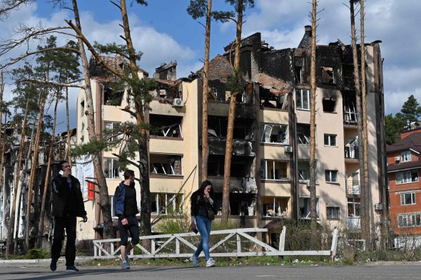 Пішоходи проходять повз зруйнований житловий будинок в Ірпені 