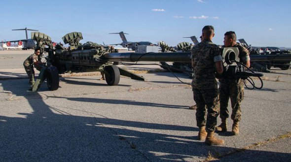 Американські морські піхотинці тягнуть до літака буксировані 155-мм гаубиці М777. Зброя готова до відправлення в Україну.