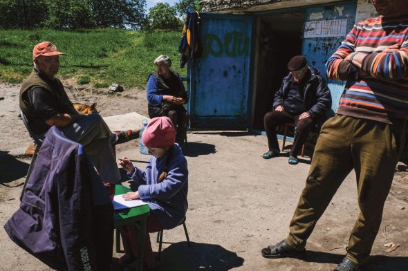 Люди сидять біля укриття в Лисичанську на Луганщині 23 травня. Через часті обстріли не відходять від нього далеко