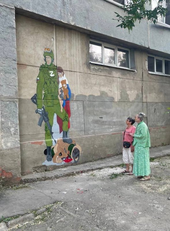 На цьому "творі мистецтва" окупант обіймає дівчинку і топче її вбитого батька