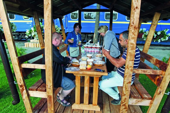 Люди обідають в дерев’яній альтанці на території ”Залізного міста” в Ірпені під Києвом 16 червня