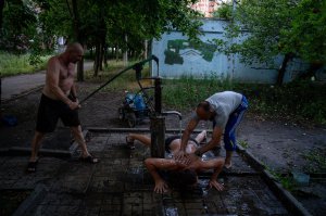 Чоловіки з житлового масиву Північна Салтівка в Харкові миються під вуличним краном, 27 липня. Район розташований на околиці міста, тому найбільше потерпає від російських обстрілів. 70 відсотків будинків зруйновані чи пошкоджені. Немає водопостачання та електрики. Попри це все більше харків’ян повертаються до своїх квартир