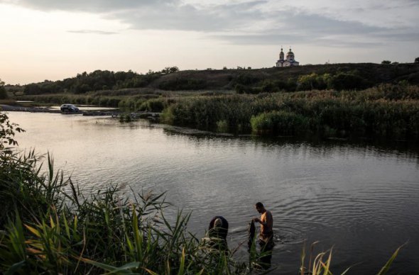 Мужчины ищут мидии в прифронтовом селе Херсонской области  