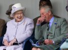Елизавета II и Карл III смеются, глядя на гонки детей в мешках, посещающих Braemar Highland Gathering 2012 года, Шотландия