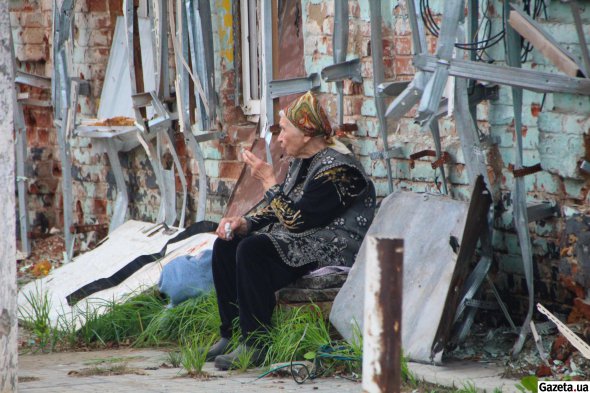 Людмила Бурмістрова сидить біля розбитої будівлі магазину, очікуючи гуманітарну допомогу в центрі Ізюма