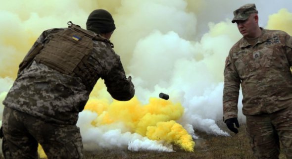 Американский военный инструктор наблюдает, как украинские военніе используют дымовые шашки во время учений в Германии в 2018 году