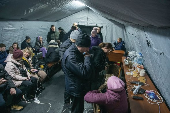 Люди гріються і заряджають телефони у пункті незламності в Києві