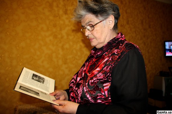 Тамара Єльянівна Ліфшиц показує у книжці фотографію плити над захороненням Тори