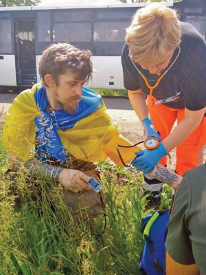 Медикиня міряє тиск і сатурацію українському військовослужбовцю, визволеному з російського полону внаслідок обміну 25 травня 2023 року