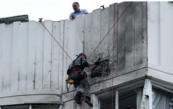 Специалист осматривает поврежденный фасад после атаки дронов по Москве