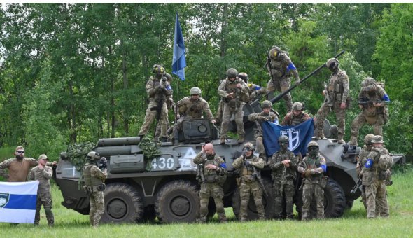 Бійці Російського добровольчого корпусу та союзного угруповання «Легіон Свобода Росії» поряд із захопленим бронетранспортером, 24 травня 2023 року 