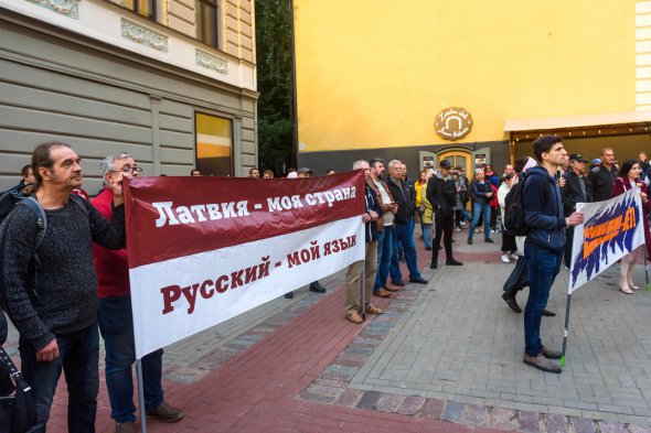 Люди тримають банер «Латвія, моя країна. Російська - моя мова» на протесті проти переходу шкіл меншин в Латвії на повне вивчення латиської, 7 вересня 2022 року, Рига. Російське вторгнення в Україну ускладнило ситуацію для російськомовних жителів Латвії