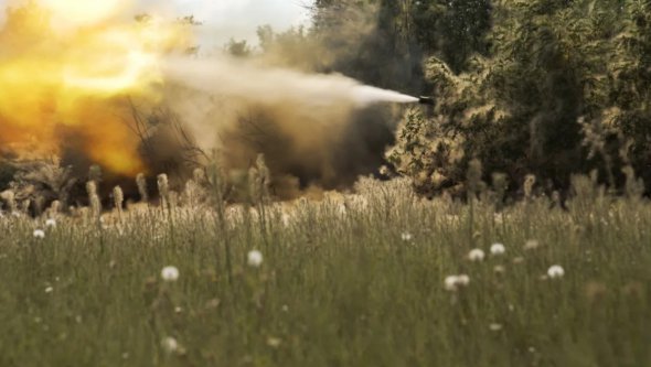 Український танк веде вогонь через смугу дерев у бік російських військ 