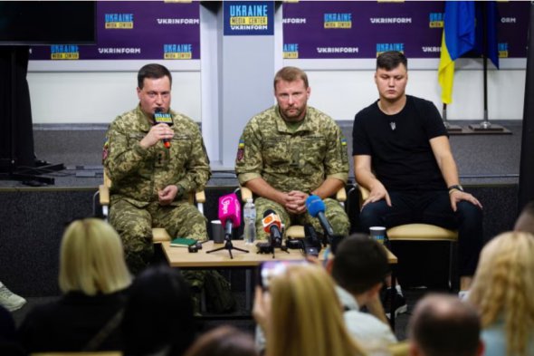 Российский пилот вертолета Максим Кузьминов (справа) на пресс-конференции с двумя украинскими военными 